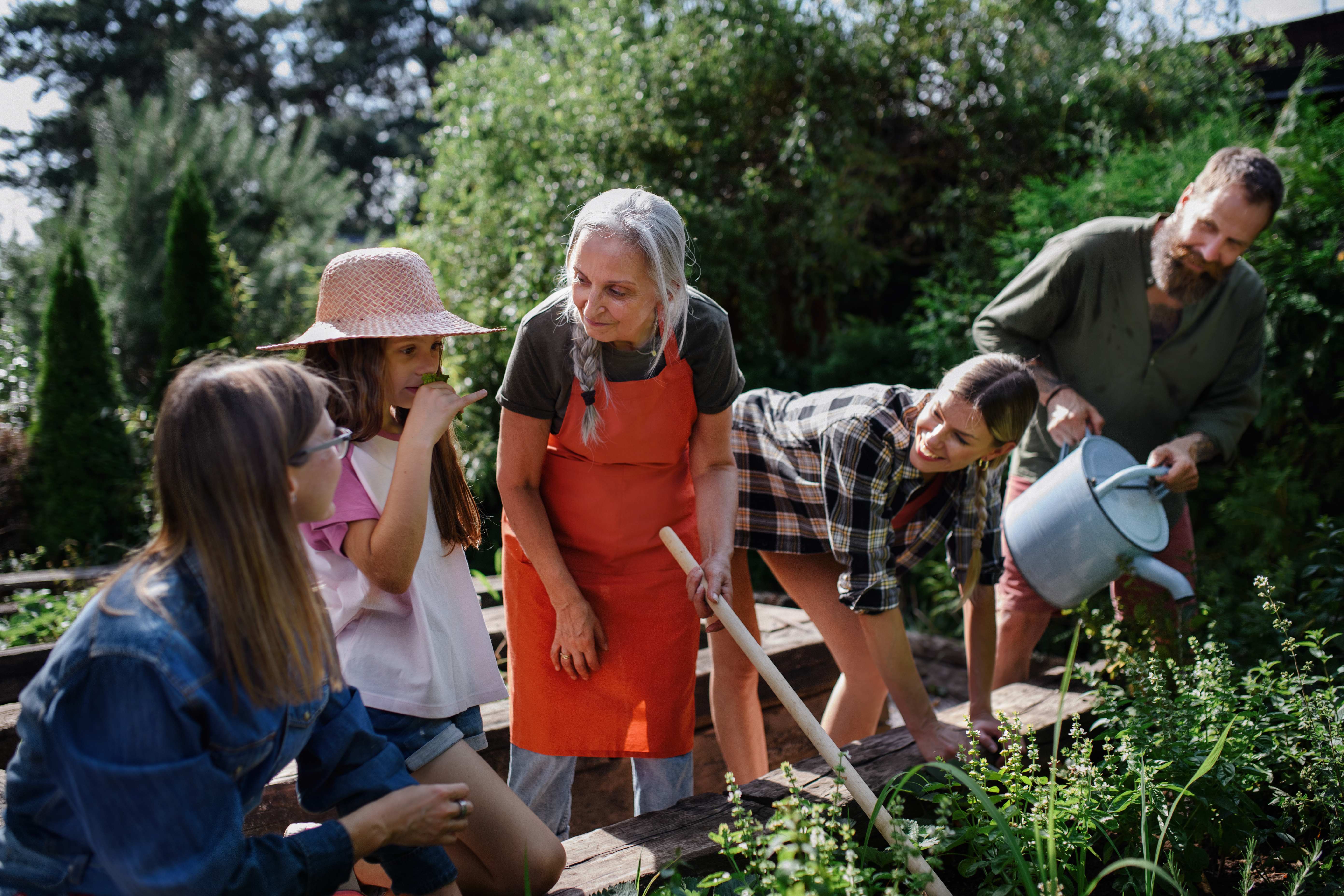 Multi-generational community members working together in community garden with raised beds